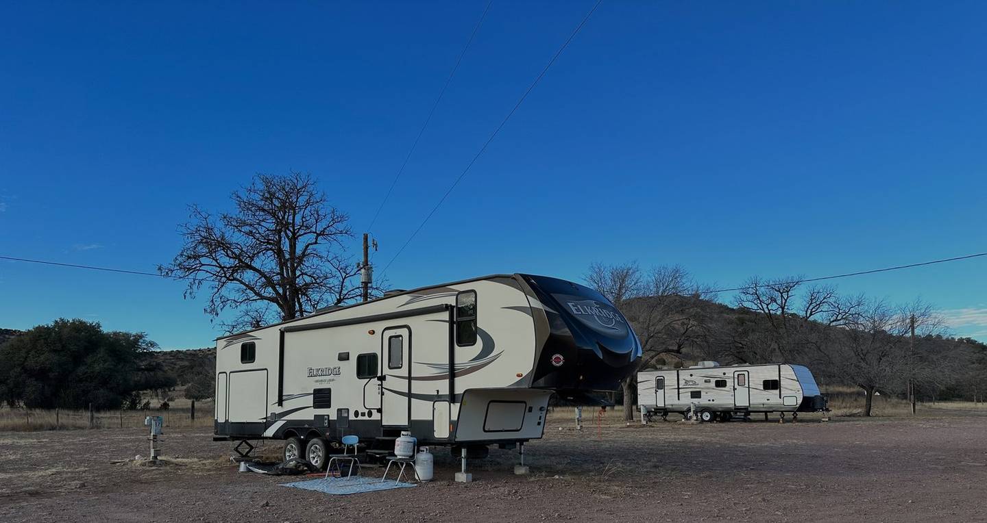 Travel trailers parked on the RV sites under a wide blue West Texas sky